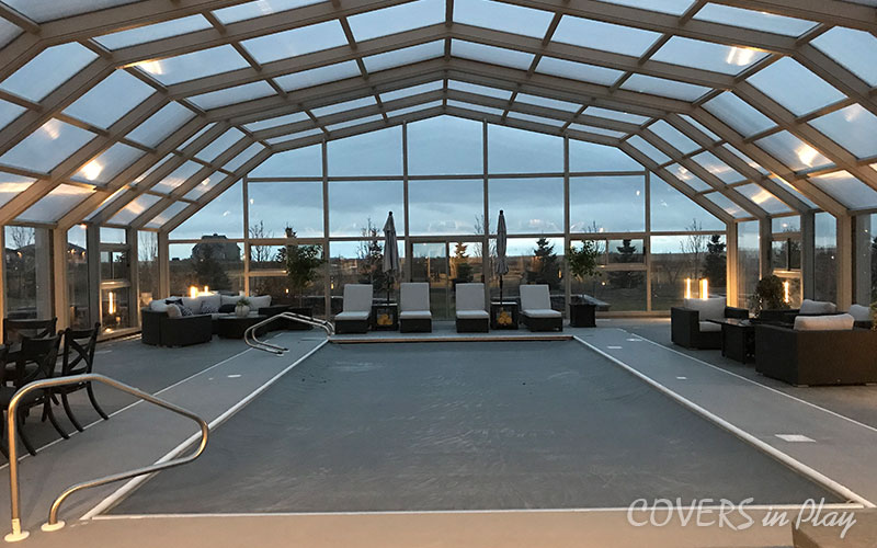Interior view of pool dome in Iron Bridge, SK, featuring ambient lighting and
            welcoming patio furniture.