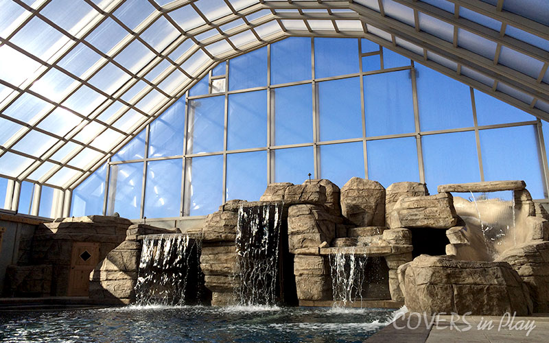 Interior view of swimming pool dome in Nephi, UT, featuring a beautiful waterfall feature and displaying the durable framing system.