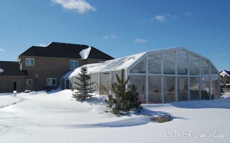 Exterior rear view of pool dome cover for winter in Sharon, ON, with snow
            surrounding the structure.
